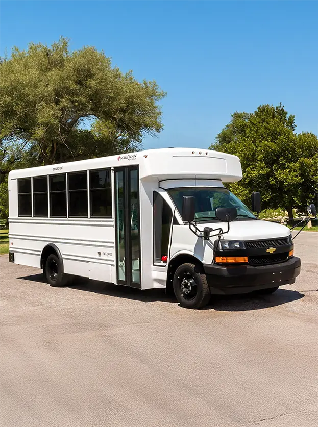 white activity bus in a parking lot with trees and a blue sky